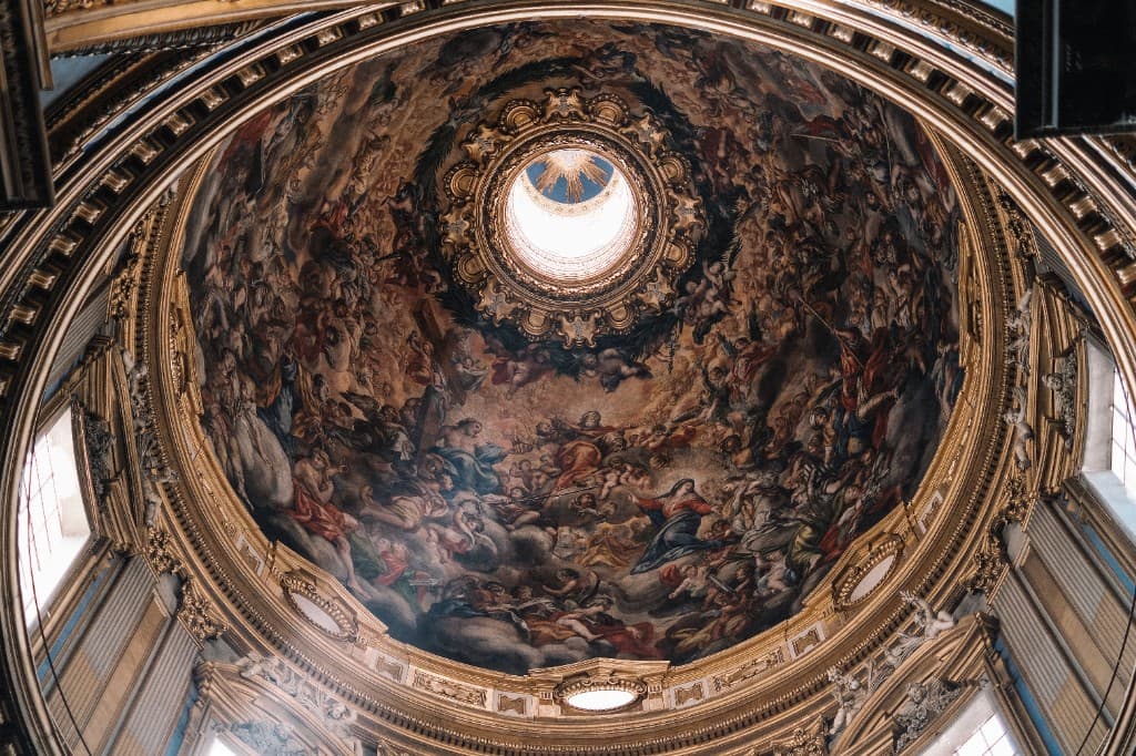 Interior of a classical dome with a baroque fresco depicting biblical figures and angels beneath a central oculus